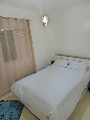 a white bed in a room with a window at Appartement neuf, propre et ensoleillé in Temara