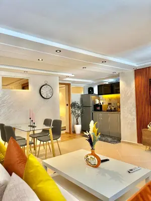 a living room and kitchen with a clock on the wall at Villa 1 Corniche, Seaside Stay at Carrousel Mall, Walk Everywhere in Rabat