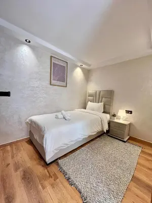 a bedroom with a large white bed and a rug at C2, Modern Charm apartment Facing Carrousel with Ocean View in Rabat