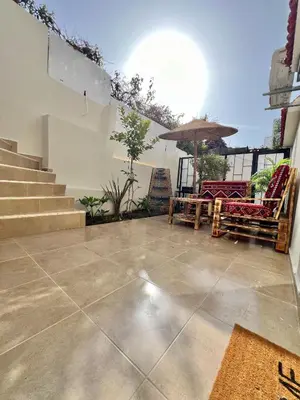a patio with chairs and an umbrella and stairs at C2, Modern Charm apartment Facing Carrousel with Ocean View in Rabat