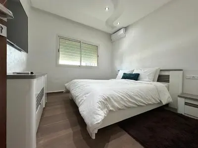 a bedroom with a large white bed with a window at Villa de luxe avec piscine et jardin privés in Temara