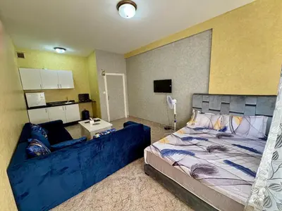a bedroom with a large blue bed and a kitchen at Dar Raciki Elikya in Rabat