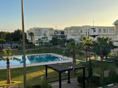 a view of a swimming pool with palm trees and buildings at Magnifique Appartement Bahia Golf Beach in Bouznika