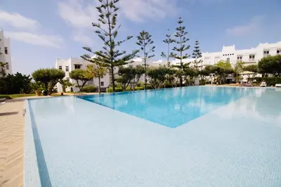 a large swimming pool with blue water at Magnifique studio cosy et lumineux avec vue sur mer in Tamaris