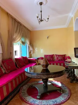 a living room with a pink couch and a table at Bouznika 100m2 Piscineplage in Bouznika
