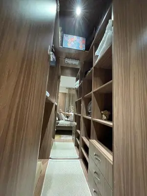 a walk in closet with wooden cabinets and a television at Beautiful apartment with pool in Mansouria