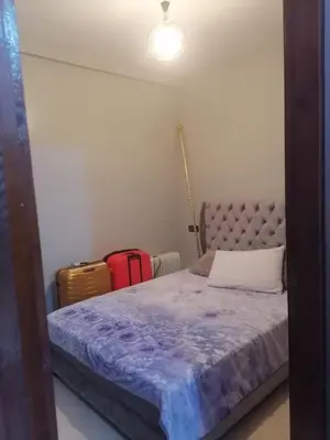 a bedroom with a bed with a purple comforter and a suitcase at 50m RDC aliace darna louizia in Mohammedia