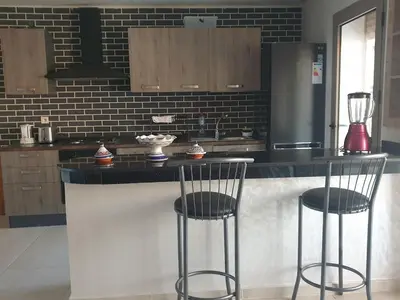 a kitchen with a counter with two bar stools at Sunny modern Apartment- Ocean & Pool view in Al Mansouria in Mansouria