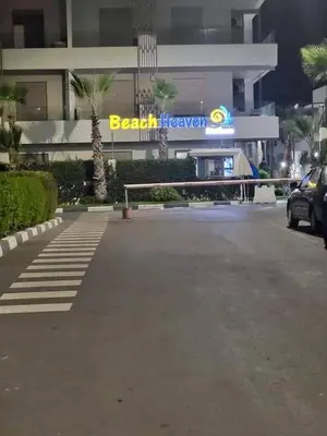 a parking lot in front of a building with a sign at Seaside escape beautiful garden apartment in Sidi Rahal