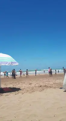 a group of people on a beach with an umbrella at Sidi rehal in Sidi Rahal