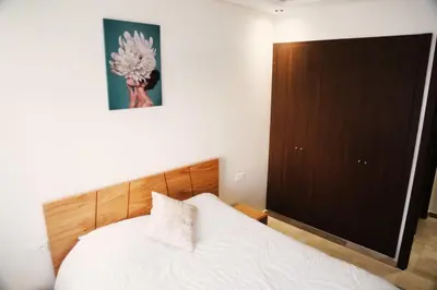 a bedroom with a white bed and a brown cabinet at Studio haut standing CASA in Aïn Harrouda