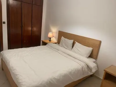 a bedroom with a white bed with a wooden headboard at Chic Studio in Agdal Walk to Everything in Rabat