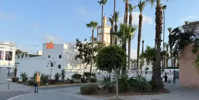 a person walking down a street with palm trees at Charmante Maison Traditionnelle au Cœur de la Médina, 5 min de Casa Port in Casablanca
