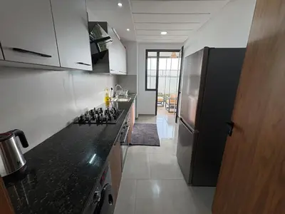 a kitchen with a black counter top and a refrigerator at Bain de soleil à Dar Bouazza in Dar Bouazza