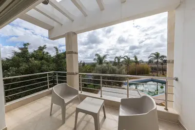 a balcony with chairs and a view of a pool at Asmae House in Skhirat