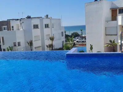a large blue swimming pool next to a building at Appartement de plage front de mer in Tamaris