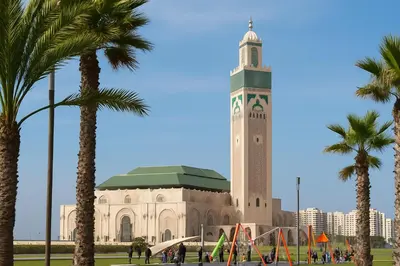 a large building with a clock tower with palm trees at Cosy ensoleillé 2CH proche de Mosquee hassan II et corniche in Casablanca