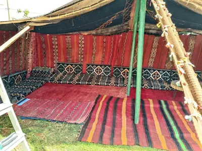 an interior of a tent with colorful rugs at Ferme