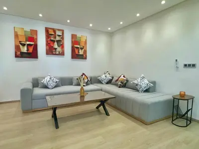 a living room with a couch and paintings on the wall at 2br near TGV station in Rabat