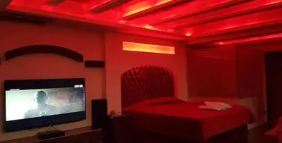 a red room with a bed and a flat screen tv at Appartements journaliers et mensuels in Aïn Chock