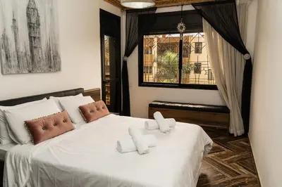 a bedroom with a bed with white sheets and a window at Family apartment with balcony and Netflix in Temara