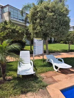 two white chairs sitting in the grass near a building at Résidence balnéaire Les perles de Tamaris in Tamaris