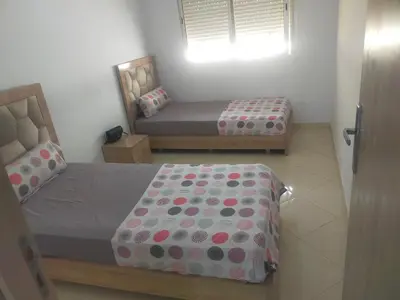 a small bedroom with two beds and a window at Appartement calme et confortable in Bouznika