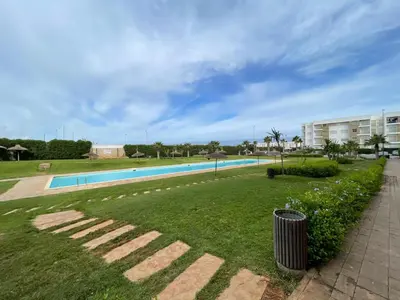 a swimming pool with a trash can in the grass at APPART AMIR Belle Appartement avec pecine in Dar Bouazza