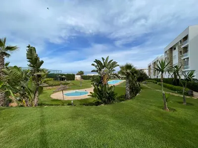 a resort with two pools and palm trees at APPART AMIR Belle Appartement avec pecine in Dar Bouazza