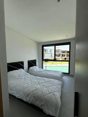 a bedroom with two beds and a large window at Sidi Rahal Oceanic Appartement vue sur piscine in Sidi Rahal