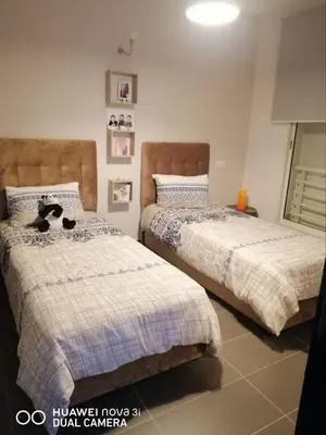 a bedroom with two beds with a cat sitting on them at Appartement Résidence balnéaire Dar Al bahr in Sidi Rahal