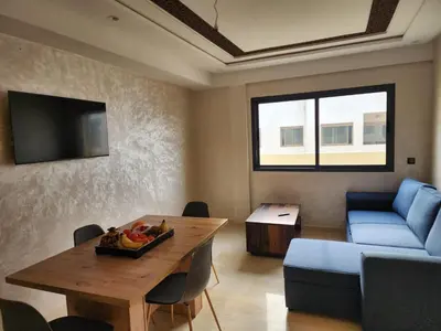 a living room with a table and a blue couch at Bab fes Appartement 2 pièces à Aïn Sebaâ Casablanca in Aïn Sebaa