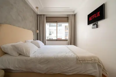 a bedroom with a white bed with a clock on the wall at Central Cosy 2BR 2 Baths, Balcony & Clear View in Casablanca