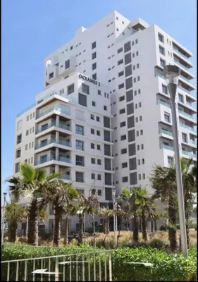 a large white building with palm trees in front of it at Terrasse Horizon Marina in Casablanca