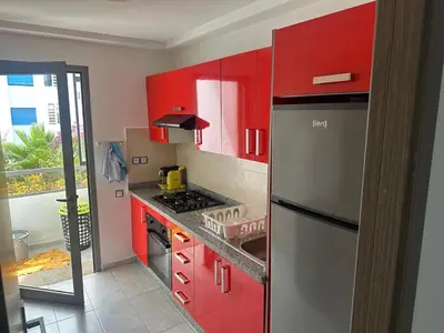 a kitchen with red cabinets and a stainless steel refrigerator at Seaside apartment in El Mansouria in Mansouria