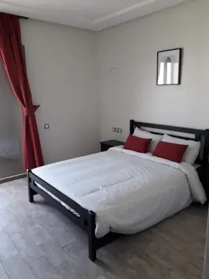 a bedroom with a large bed with red pillows at Seaside apartment in El Mansouria in Mansouria