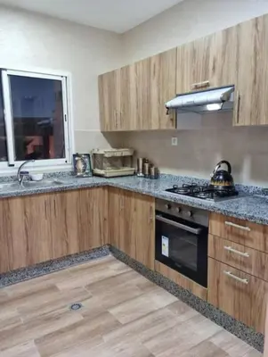 a kitchen with wooden cabinets and a stove top oven at Appartement de luxe avec piscine à Mansouria in Mansouria