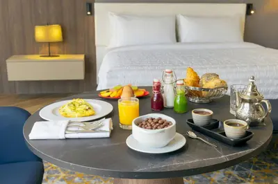 a breakfast table with breakfast foods and drinks on a bed at Le Meridien Casablanca in Casablanca