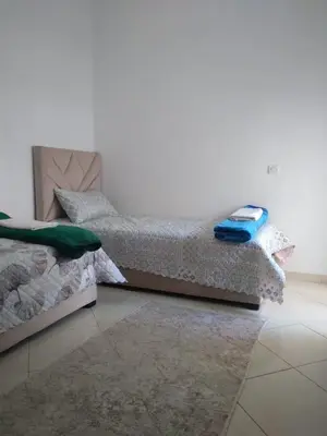 a bedroom with two beds and a white wall at Appartement à Skhirat in Skhirat