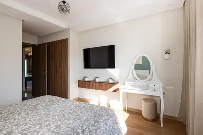a white bedroom with a bed and a mirror at Chic, bright, 2 BR apartment, panoramic view & Parking in Temara