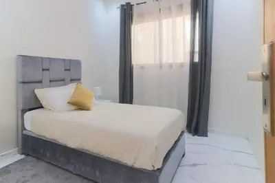 a bedroom with a bed with a gray headboard and a window at Maison Safran à Bouznika calme confort et authenticité à deux pas de la plage in Bouznika