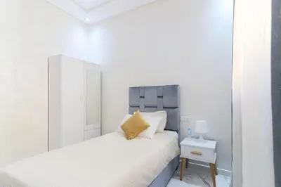 a white bedroom with a bed and a mirror at Maison Safran à Bouznika calme confort et authenticité à deux pas de la plage in Bouznika