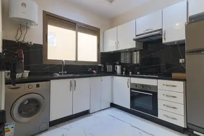 a kitchen with white cabinets and a washing machine at Maison Safran à Bouznika calme confort et authenticité à deux pas de la plage in Bouznika