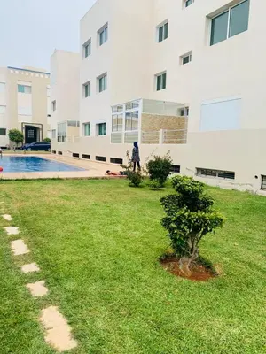 a person walking in a yard next to a building at Superbe appartement en résidence avec piscine in Mohammedia