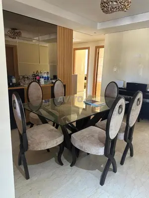 a glass dining room table with four chairs and a mirror at Appartement Souissi avec 3 chambres in Rabat