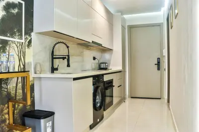 a white kitchen with a washer and dryer in it at Studio Luxe avec Vue sur la Corniche in Casablanca