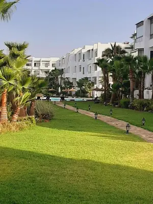 a group of birds walking in a park next to a building at Mansouria Beach Resort in Mohammedia