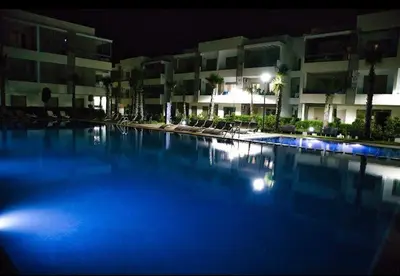 a large blue swimming pool at night with buildings at KST Home-Heaven Beach Sidi Rahal in Sidi Rahal