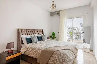 a white bedroom with a large bed with blue pillows at Luxury Garden View Apartment Private Floor in Casablanca
