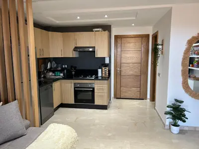 a kitchen with wooden cabinets and a stove top oven at Appartement de luxe vue sur mer in Bouznika
